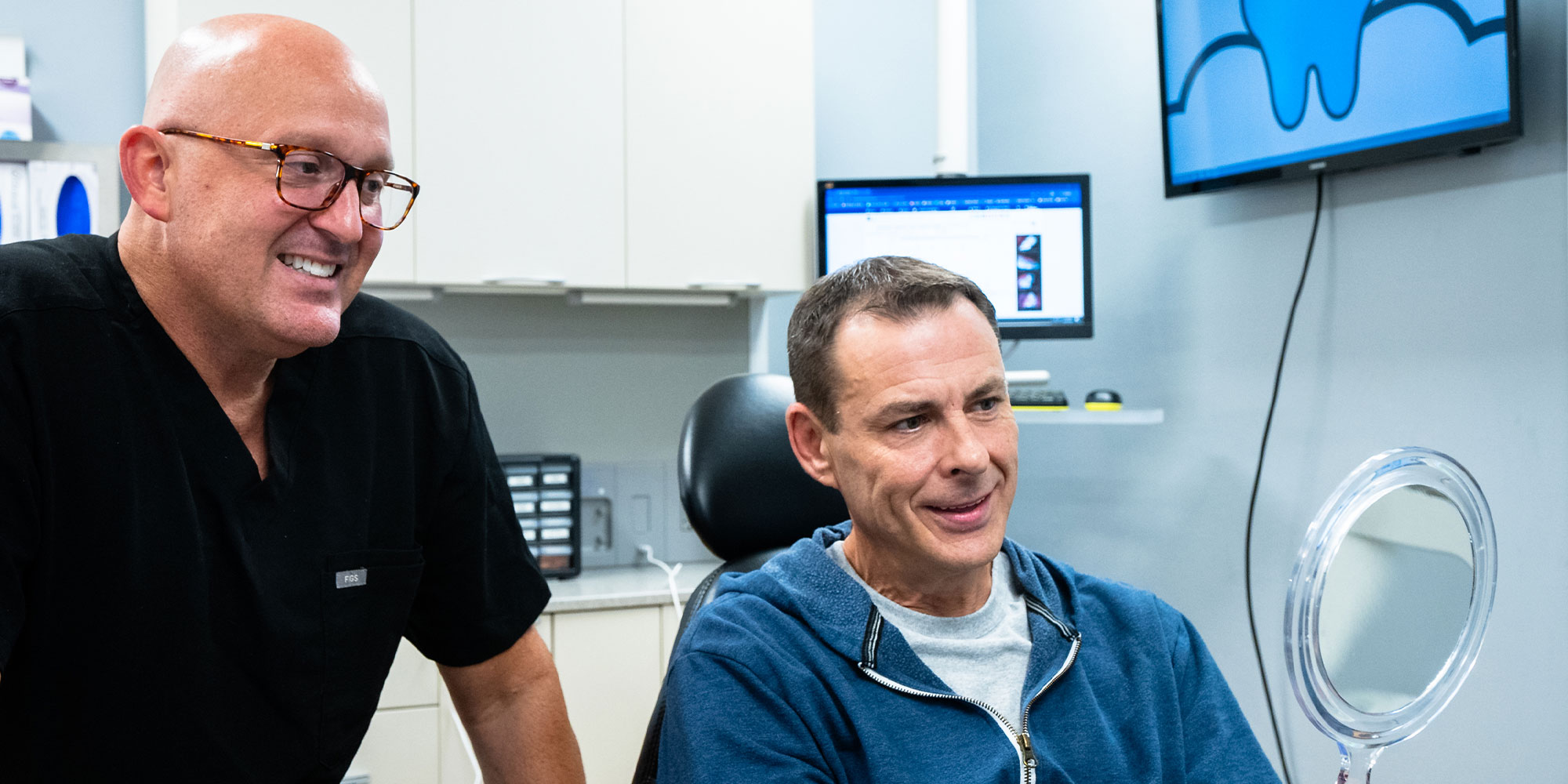 Dr. R. Benjamin Scott showing patient their teeth after procedure