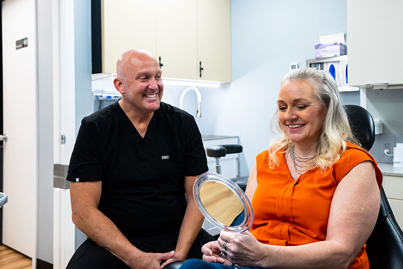 Dr. R. Benjamin Scott showing patient their teeth after dental procedure