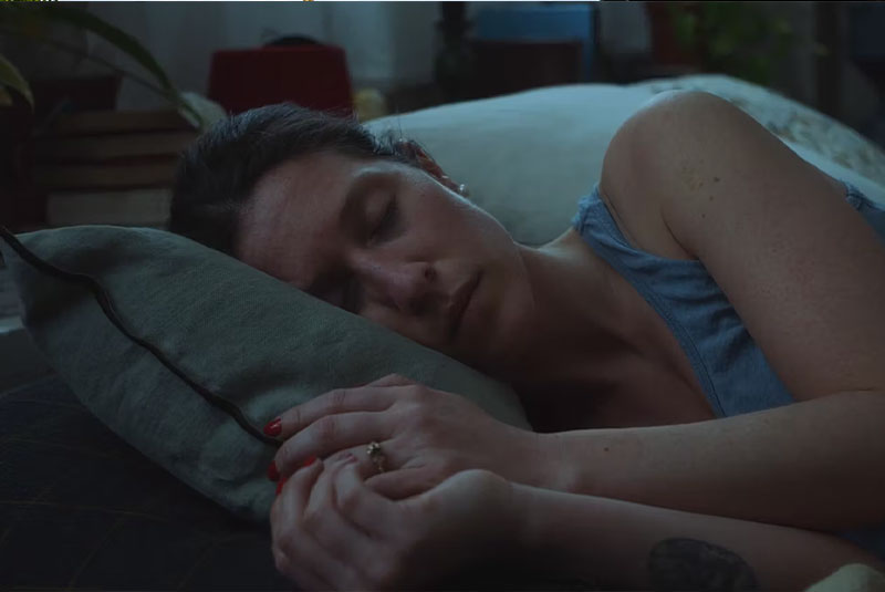 A woman is sleeping in her bed. She is dreaming of a beautiful beach.