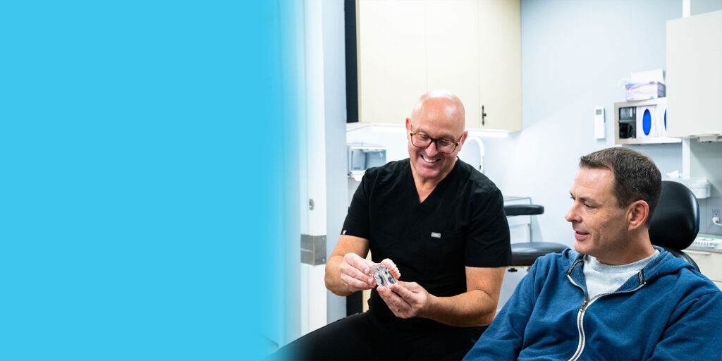 Dr. R. Benjamin Scott showing a patient a model of implants